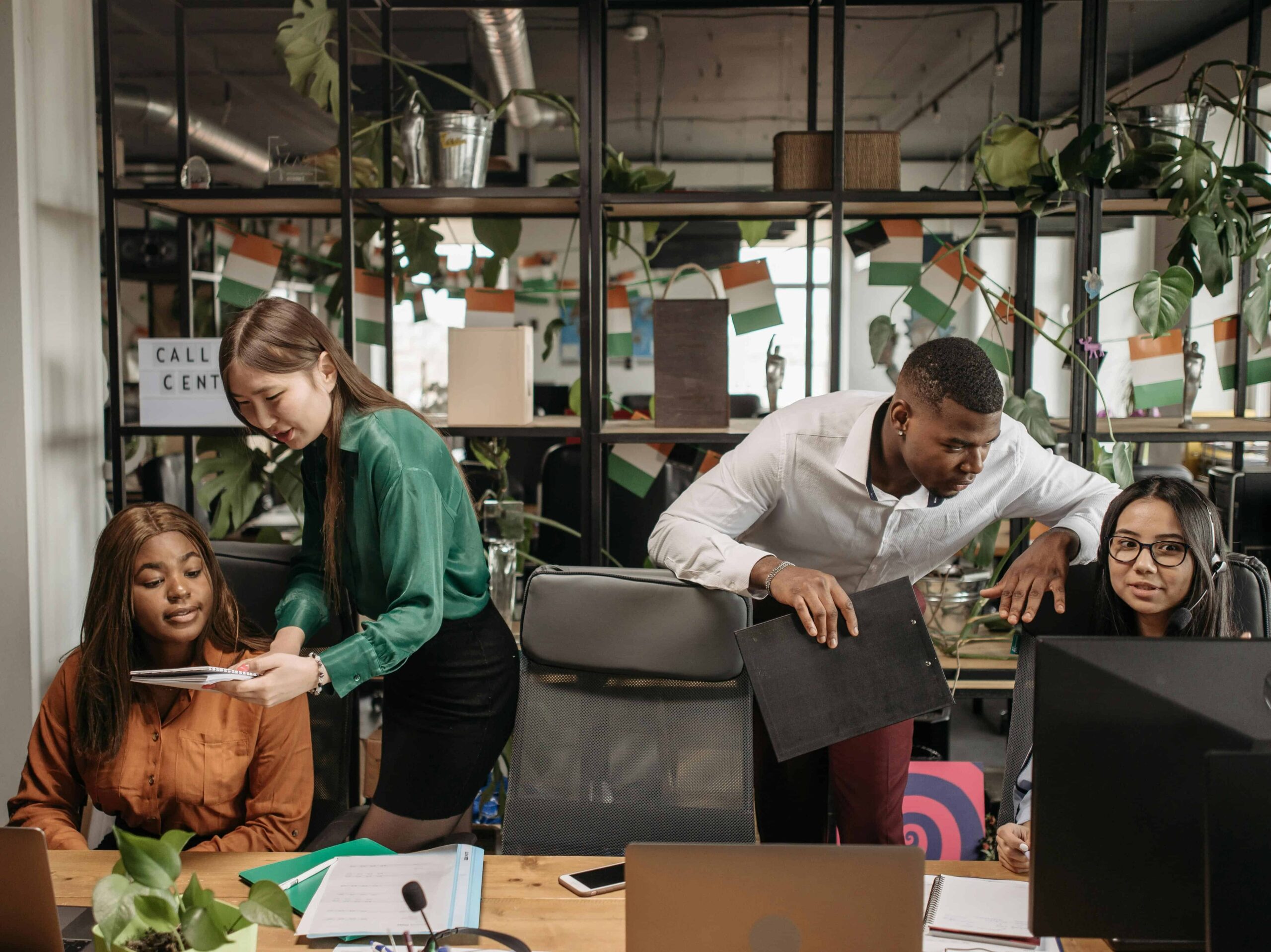 people in an office setting helping each other with work on their computers