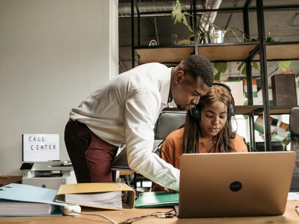 A man standing discussing work with a woman seated down